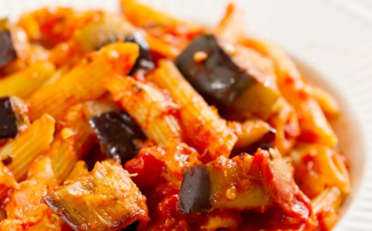 primo piano di pasta condita con pomodoro e melanzane